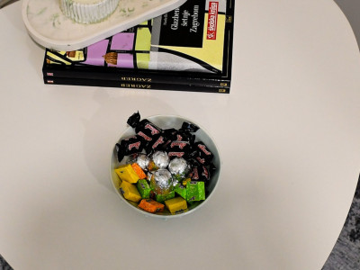 Mali pomoćni stol s bombonima i zapaljenom sojinom svijećom.