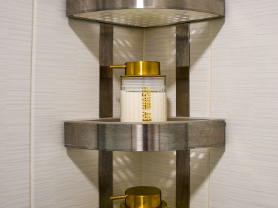 Set sredstava za tuširanje u staklenim bočicama smještenim na polici.