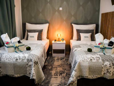 Dva jednokrevetna kreveta s bijelom posteljinom u modernom apartmanu.