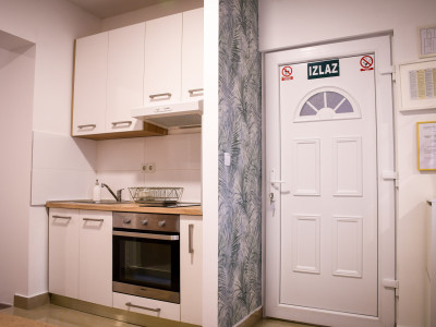 Ulazna vrata u apartman i pogled na dio kuhinje s pećnicom i sudoperom